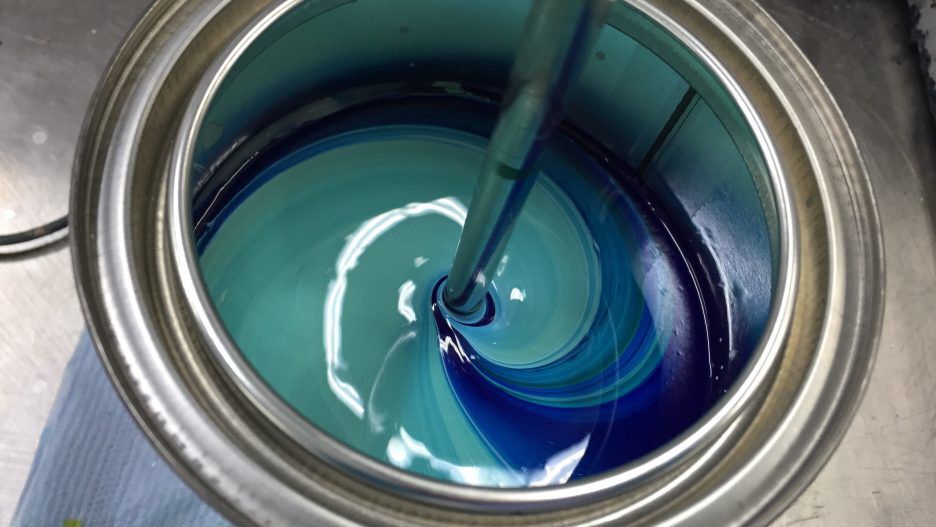A mixing blade dispersing pigments in a container.