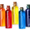Five clear bottles with food inks colored in orange, red, yellow, blue, and purple.
